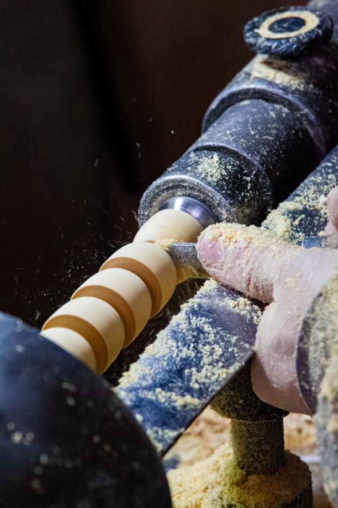 Master woodworker hand-turning a custom wood spindle on a lathe